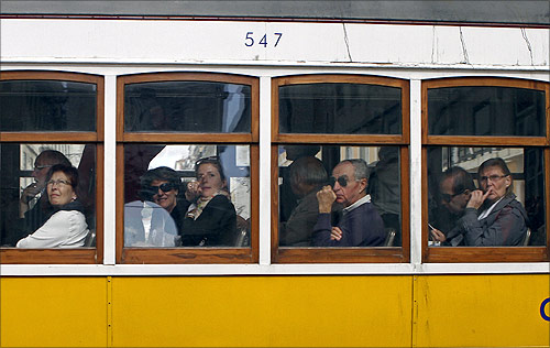 Passengers look outside from a tram in Lisbon.