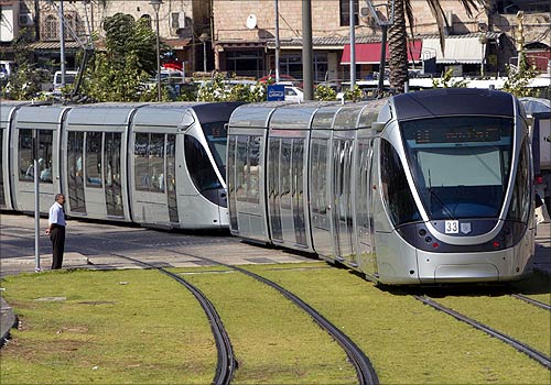 A pedestrian looks as a light rail tram passes by in Jerusalem.