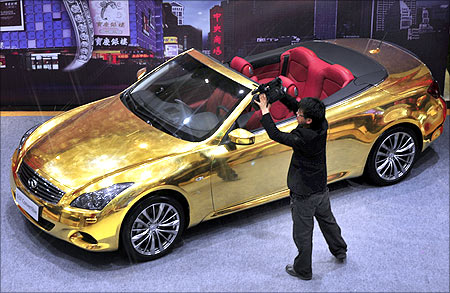 A man films a gold-plated Infiniti G37 at a jewelry store in Nanjing, Jiangsu province.