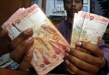 A money changer shows Malaysian ringgit notes at his shop in Putrajaya.