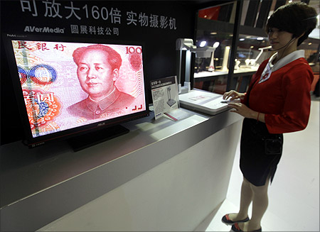 An employee operates a camera to zoom in on the image of a Chinese one-hundred yuan banknote at a production exhibition in Wuhan.