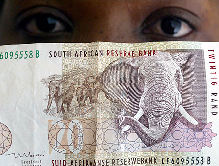 A bank teller looks at South African rand note.