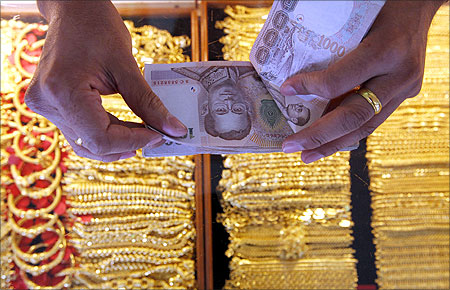 A shopkeeper counts Thai baht banknotes as he buys gold from a customer in Bangkok's Chinatown.