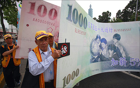 Protesters carry a banner printed with the new Taiwan dollar currency.
