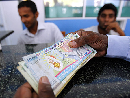 A customer holds Sri Lankan rupee notes as he waits for more cash from a teller at a money exchange in Colombo.