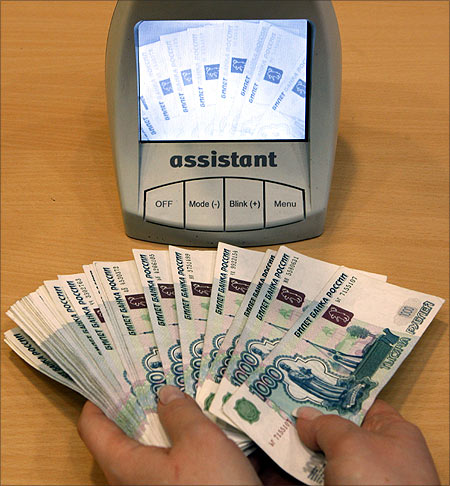 An employee of a bank checks the authenticity of Russian rouble banknotes.