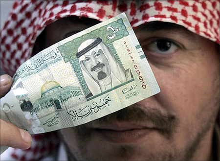 A man holds a 50 riyal ($13.3) note, which shows the Dome of the Rock in Jerusalem old city and Saudi's King Abdullah.