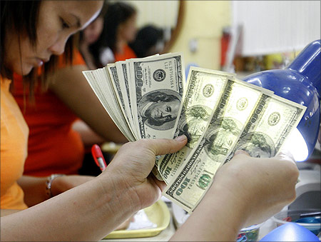 A worker checks $100 bills at a money changer in Manila.