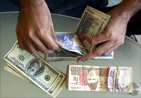 A currency dealer counts Pakistani rupees and U.S. dollars at his shop in Karachi.
