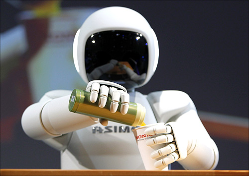 Honda Motor Co's Asimo humanoid robot pours a drink into a cup during a news conference at the 42nd Tokyo Motor Show in Tokyo.