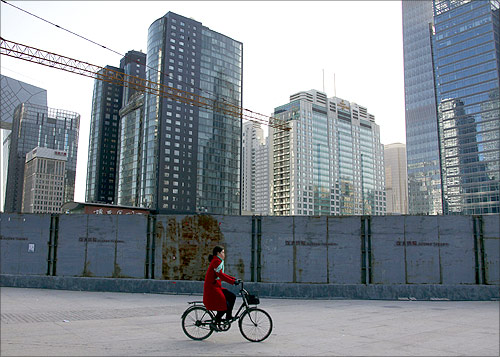 A woman cycles past new buildings and others that are still under construction in central Beijing.