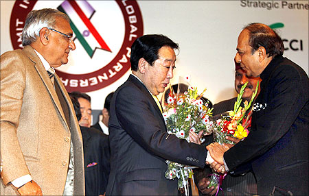 Japan's Prime Minister Yoshihiko Noda (C) shakes hands with Indian Railway Minister Dinesh Trivedi (R).