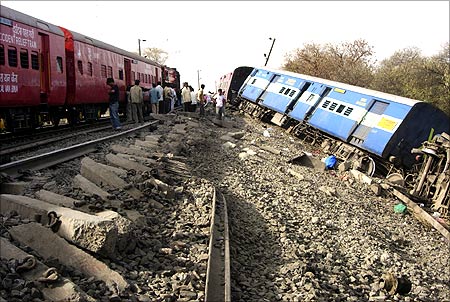 Railway officials and onlookers stand near damaged railway tracks after a passenger train derailed in Vidhisha district.