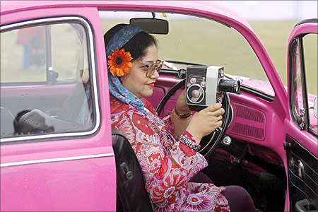 A participant uses a Bolex P4 camera while sitting inside her 1970 Volkswagen 1,285cc classic car in Kolkata.