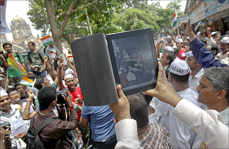 A man uses an iPad to shoot video of supporters of veteran Indian social activist Anna Hazare during an anti-government rally in Mumbai.