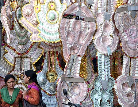 Women stand next to a shop selling garlands made of Indian currency notes in Jammu.