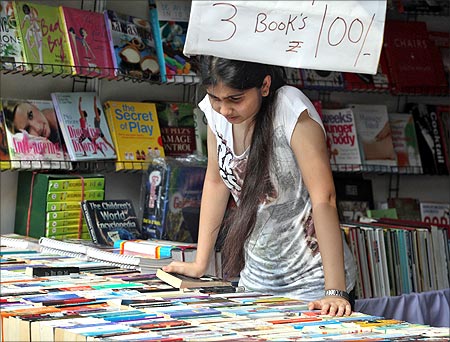 A girl looks at books at a stall selling books.