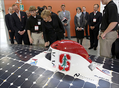 German Chancellor Angela Merkel (C) looks at a solar car.