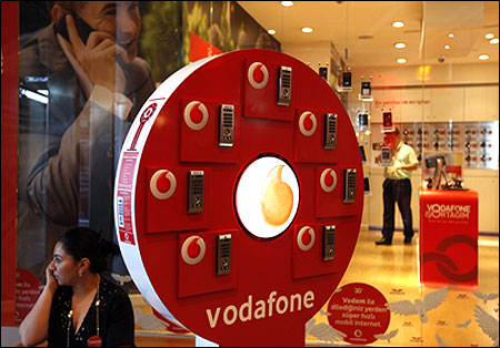 A woman talks on her mobile phone in front of a Vodafone store in Istanbul.
