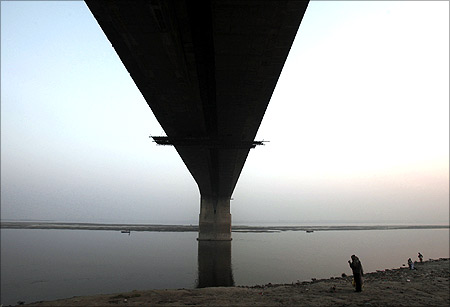 A man stands under the Mahatma Gandhi Setu bridge built over river Ganges.