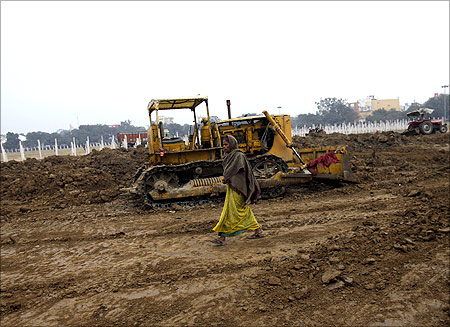 A woman walks past a bulldozer at a park being renovated in Patna.