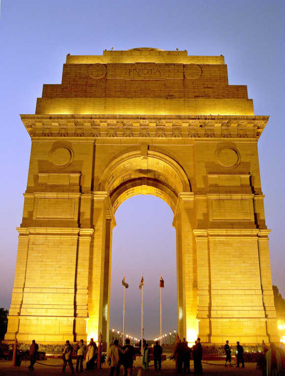 People walk near the historic India Gate during evening in New Delhi.
