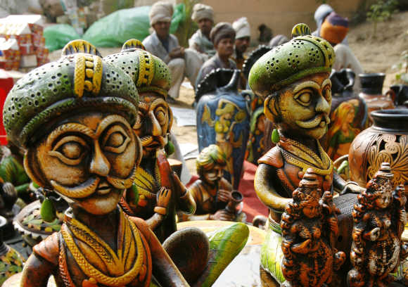 Labourers sit near a stall of sculptures at Surajkund Crafts Fair in Haryana.