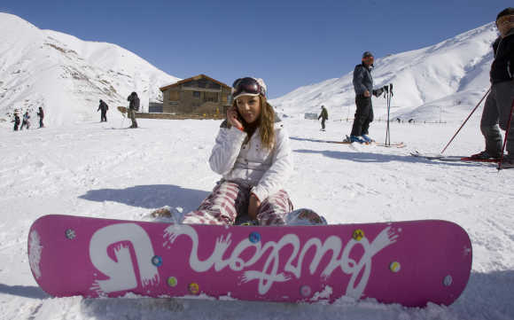 A woman speaks on her mobile phone at the midway point of a slope at Shemshak ski resort, Iran.