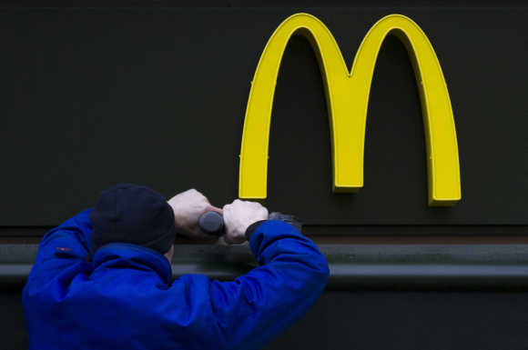 A worker drills a hole underneath the McDonald's brand sign at a store of the global fast food chain in Berlin.