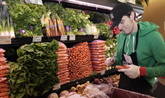 Whole Foods grocery store worker Tim Owen trims the tops of organic carrots in the produce section of the store in Ann Arbor, Michigan.