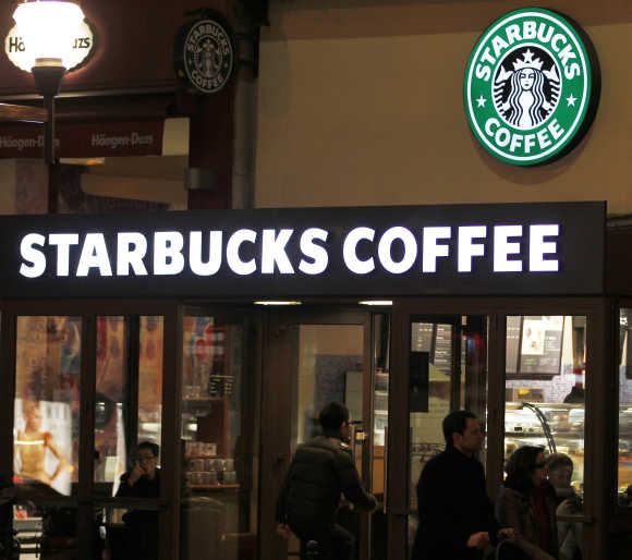 Customers are seen at a Starbucks coffee store, which displays the old logo in Paris.