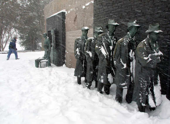 A driving blizzard blows on a Great Depression Bread-Line sculpture as a hiker walks by at the FDR Memorial in Washington, DC.