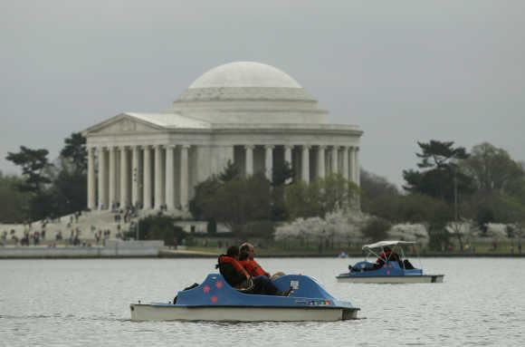 People paddle boat on the Tidal Basin with the Jefferson Memorial in the background in Washington, DC.