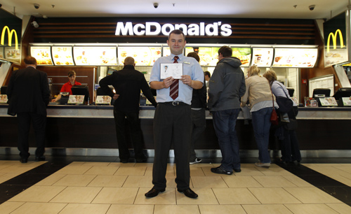 Marcin Lubowicki, a 28 year-old deputy manager of a McDonald's restaurant, poses with his university diploma in front of the fast food chain in the Arkadia shopping mall, Warsaw.