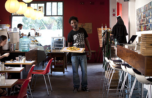 Terence Kamanda, a 25 year-old waiter, poses for a picture as he serves customers in The Corner Cafe restaurant in Durban.