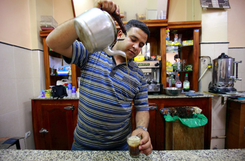 Sofiane Moussaoui, a 26 year-old waiter, poses for a picture as he serves tea for customers in a cafe in Algiers.
