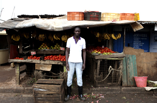 Karl Moi Okoth, a 27 year-old vegetable and fruit seller, poses for a picture in front of his makeshift shop in Nairobi's Kibera slum in the Kenyan capital.