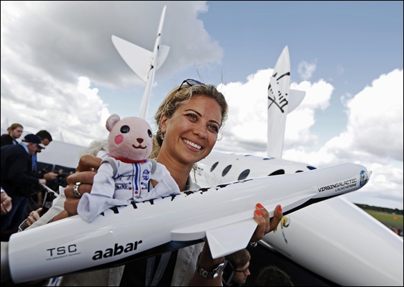 Branson's daughter, Holly, holds up a toy astronaut on top of a model of the LauncherOne cargo spacecraft.