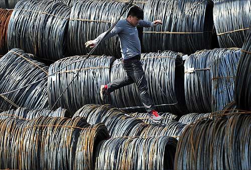 A labourer walks on coils of steel wire at a steel market in Shenyang, Liaoning province.