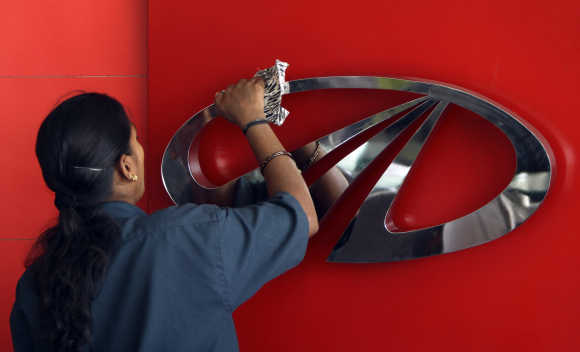 A worker cleans a logo of Mahindra & Mahindra in Chennai.