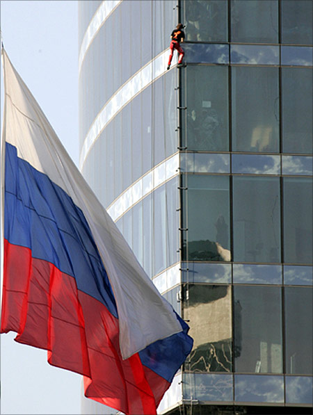 French extreme climber Alain Robert climbs the tower in Moscow as the Russian state flag is seen on the left.