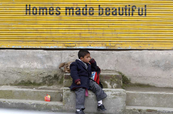 A Kashmiri school boy waits for a bus by a road side in Srinagar.
