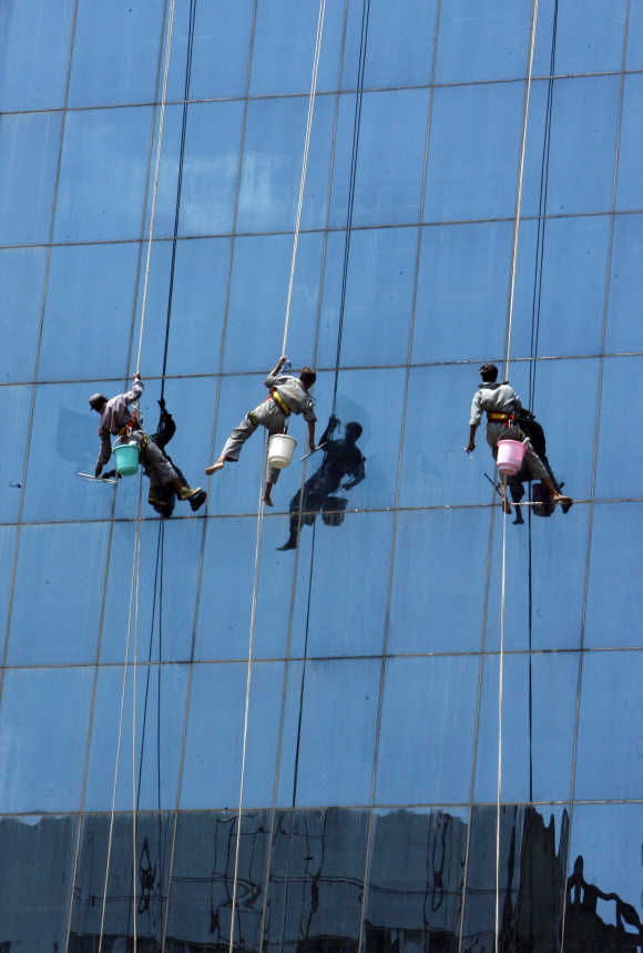 Window cleaners work on a high rising building in New Delhi.