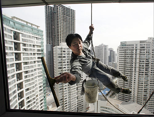A worker cleans the windows of an apartment block in Beijing's central business district.