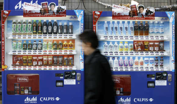 Man walks past vending machines of Asahi Soft Drinks in Tokyo.