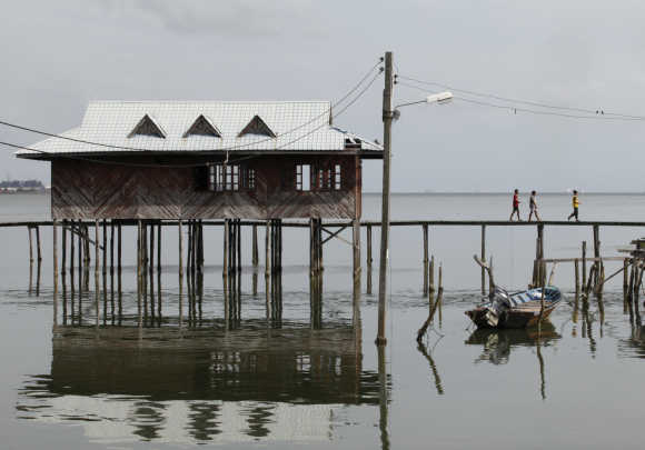 Residents walk on a wooden walkway at a water village on Malaysia's island of Labuan.