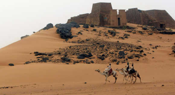 Men ride camels near the site of 44 Nubian pyramids of kings and queens in the ruins of the ancient city of Meroe next to Begrawiya, in Sudan.