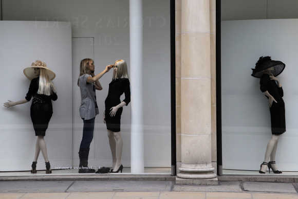 A woman combs the hair of a mannequin in a shop window in Mayfair, London.