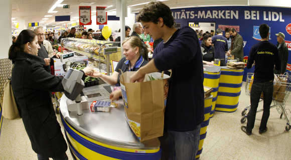 An employee packs the bag for custumer at the cash desk of a new Lidl supermarket in Zurich.