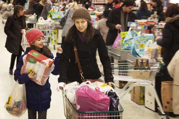 Shoppers move through the cashier area at a Morrisons supermarket ahead of Christmas weekend in London.